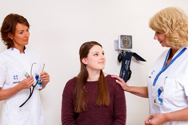 Patiënte met arts en verpleegkundige in een behandelkamer Patiënte met arts en verpleegkundige in een behandelkamer